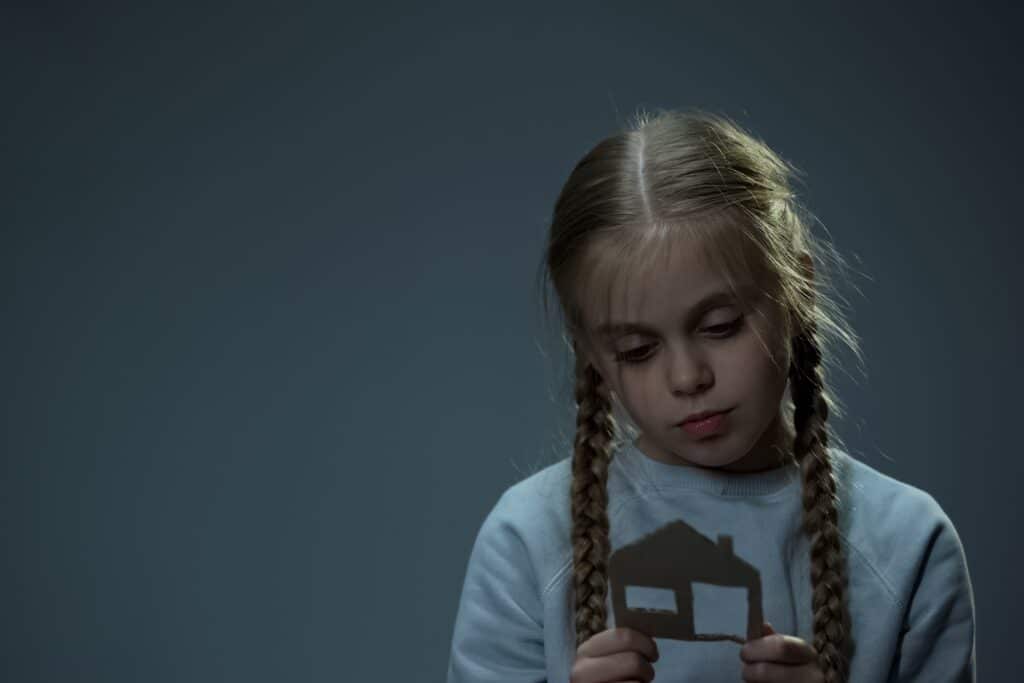 Orphan looking at cardboard house