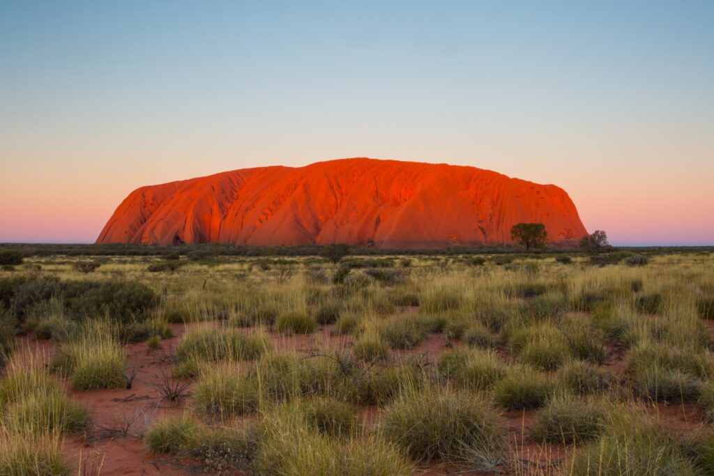Uluru glowing sienna red in the light of the sunrise or sunset
