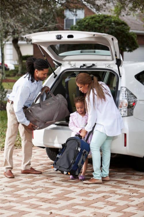 Family loading suitcases into car