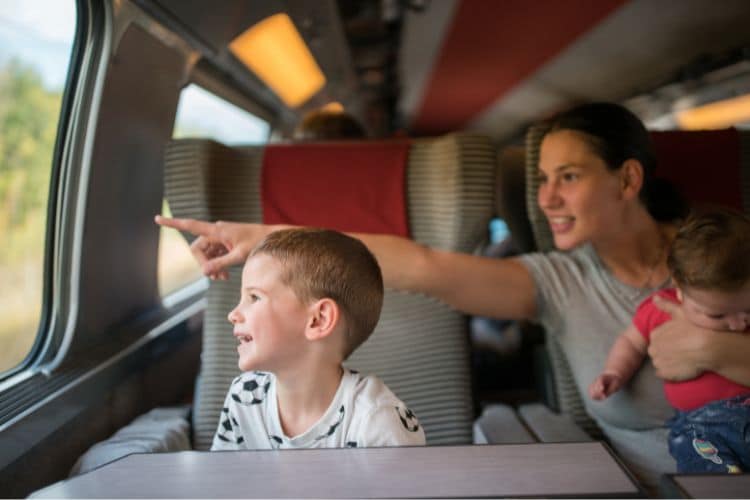 Mother on train with young children, pointing out window