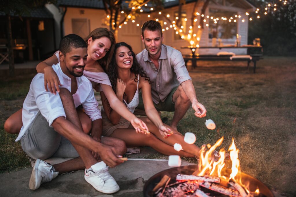 Friends roasting marshmallows by campfire