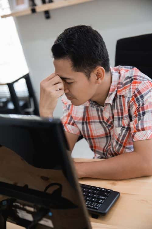 Stressed worker at computer, head in hand