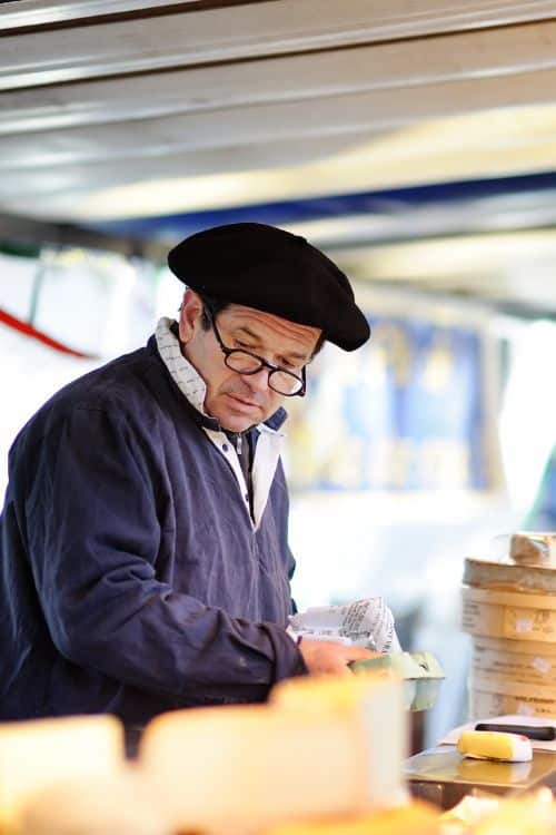 Chese Vendor at market, wearing a beret