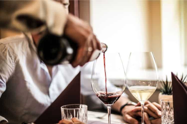 Server pouring wine into glass at restaurant
