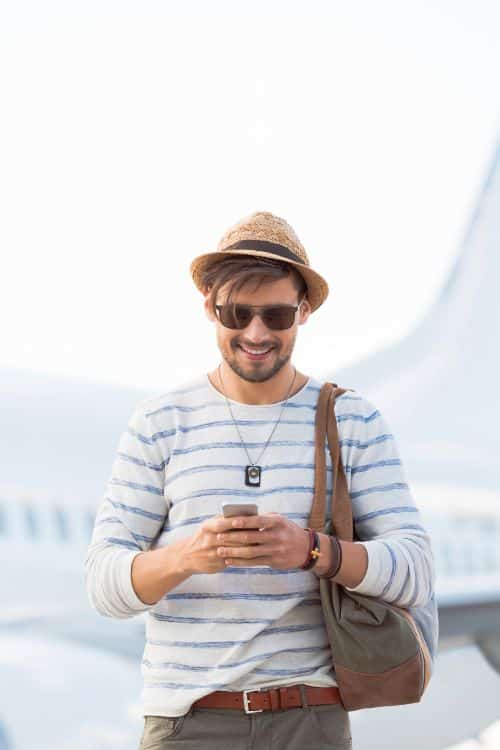 Male tourist looking at phone, airplane in background