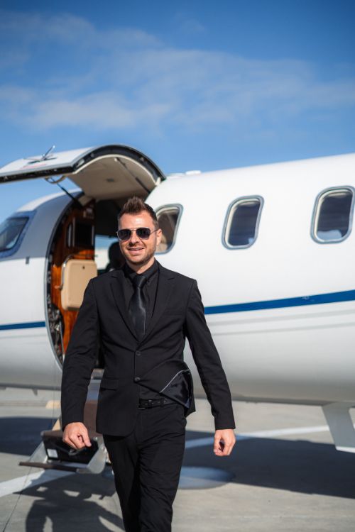 Man in a black suit, walking away from a private plane